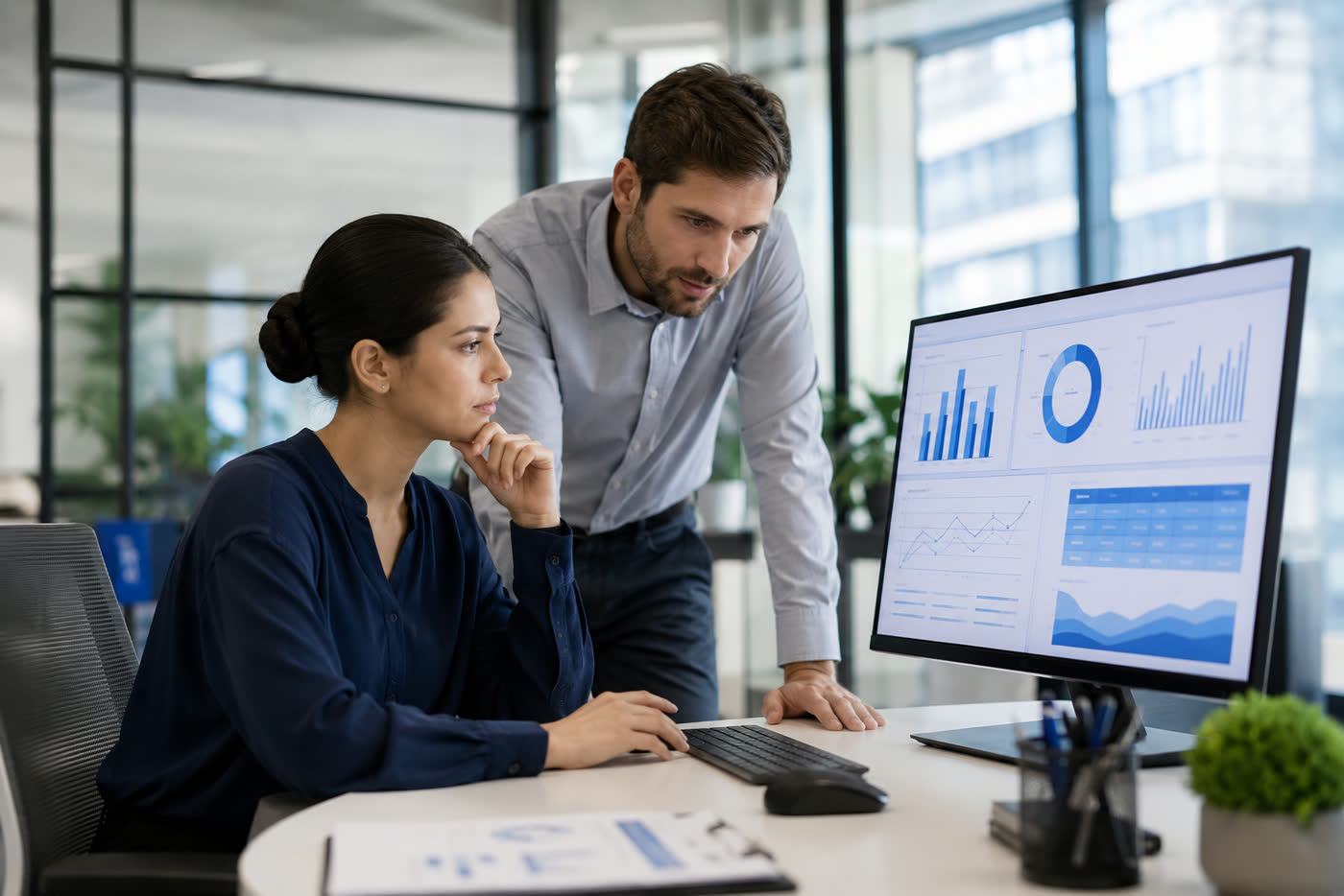 Dos personas revisando juntas un informe con gráficos en pantalla
