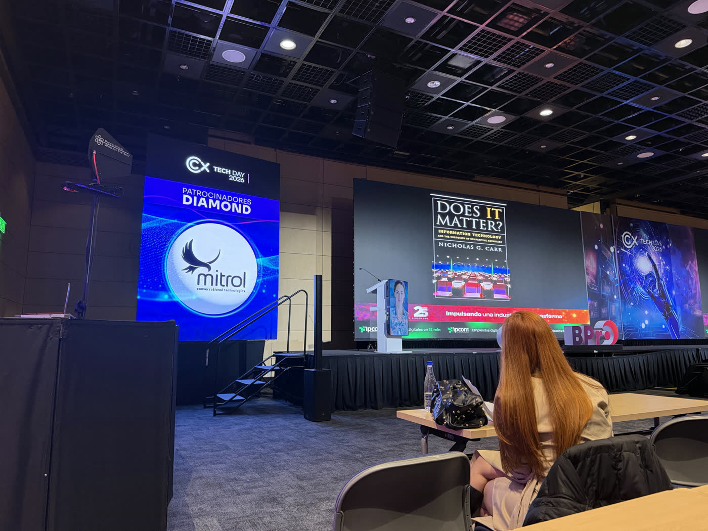 Pantalla del escenario del CX Tech Day 2026 con el logo de Mitrol entre los sponsors