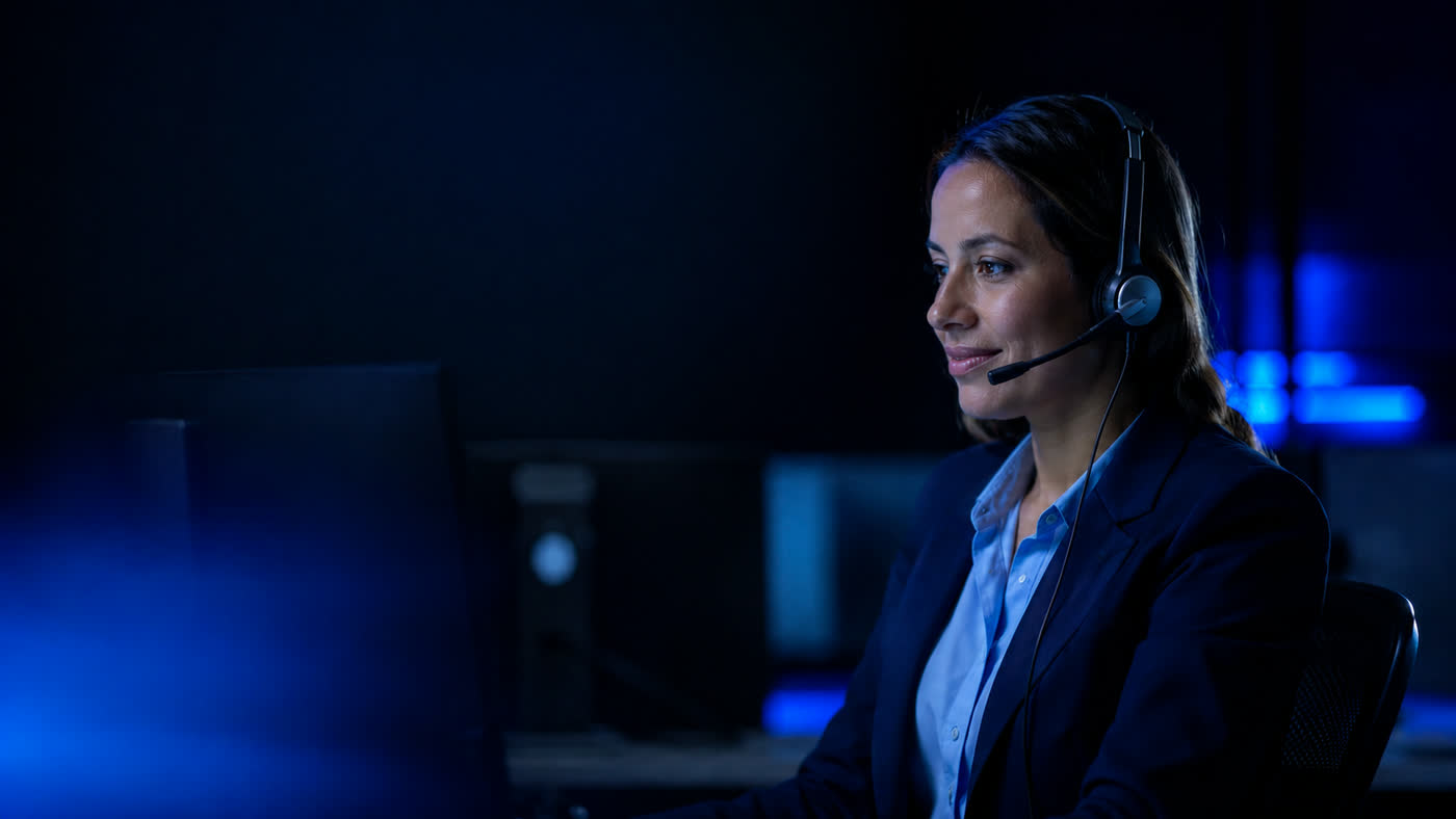 Asesora de contact center con auriculares atendiendo en su puesto de trabajo